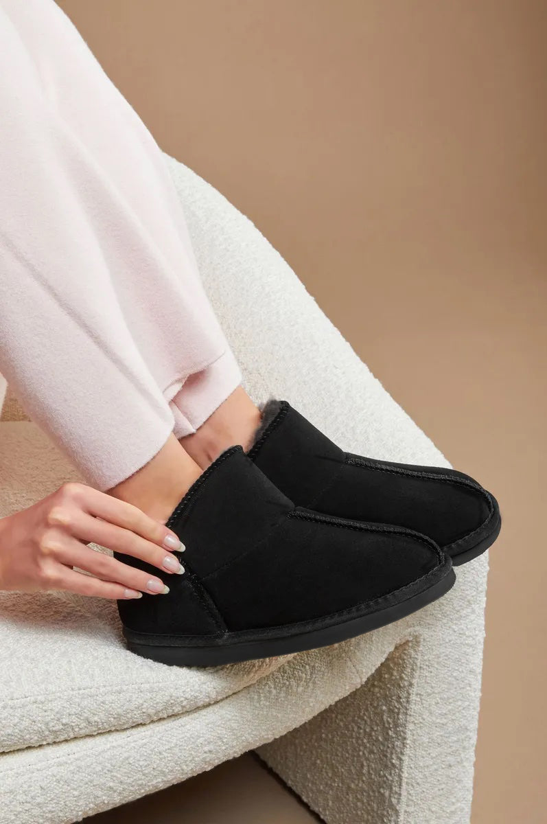 Vrouw op stoel met pantoffels dames suède look zwart met imitatiebont